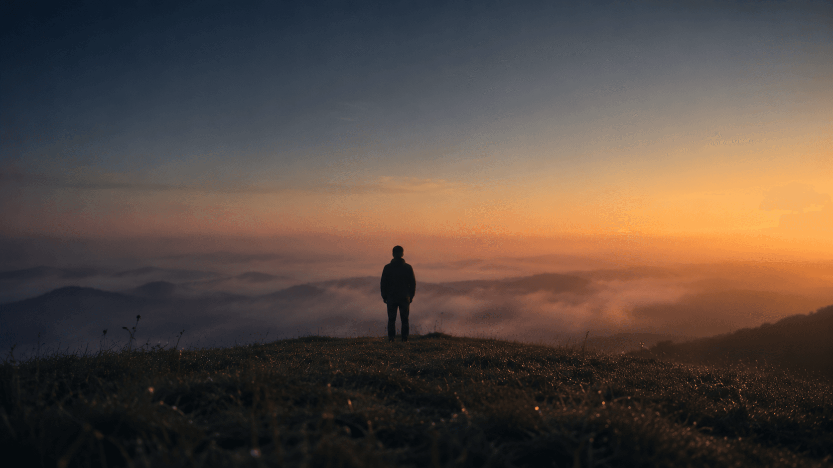 A lone figure at a misty dawn horizon